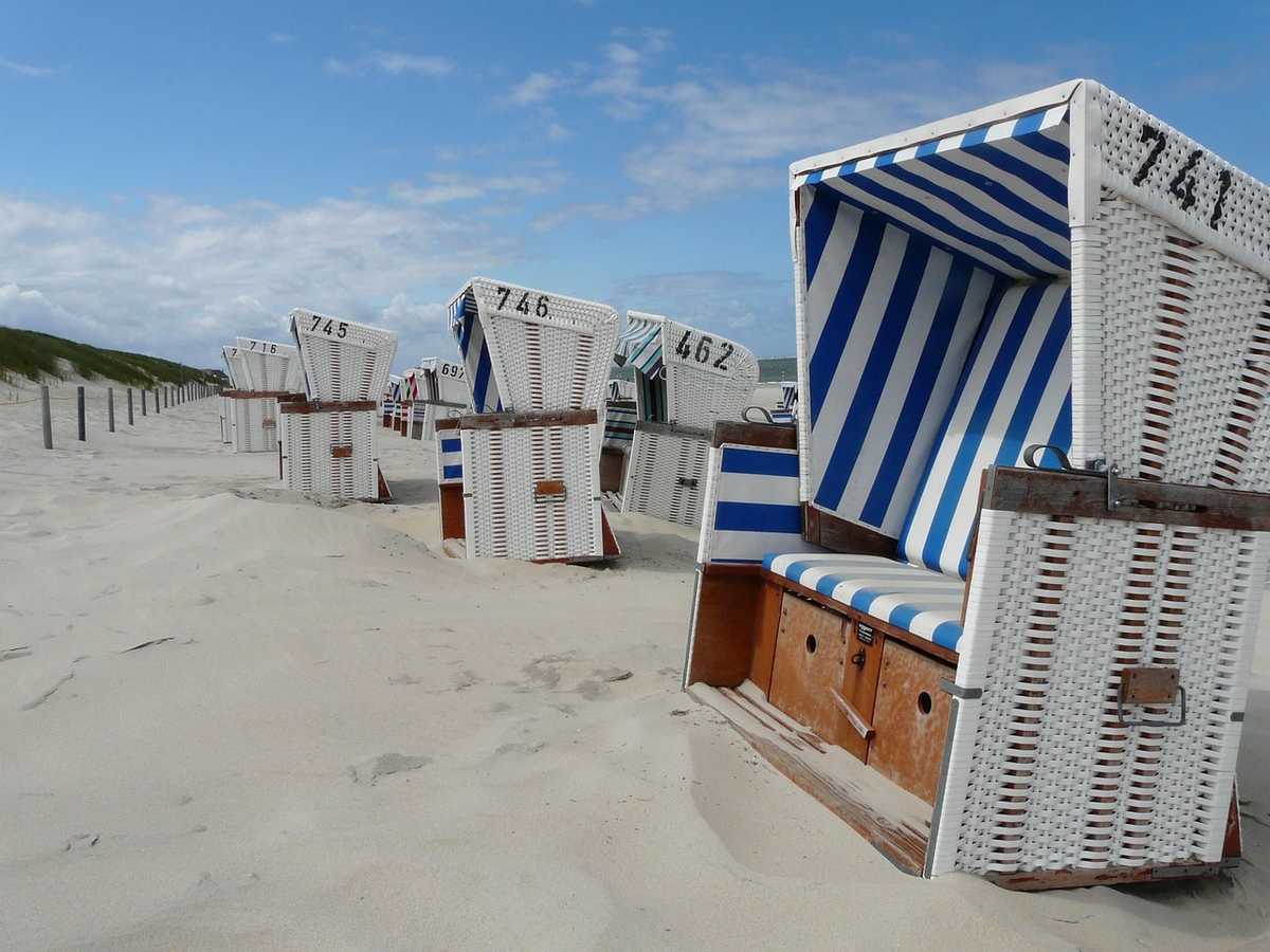 Rangée de cabines de plage rayées bleues et blanches sur plage de sable fin Rangée de cabines de plage rayées bleues et blanches sur plage de sable fin