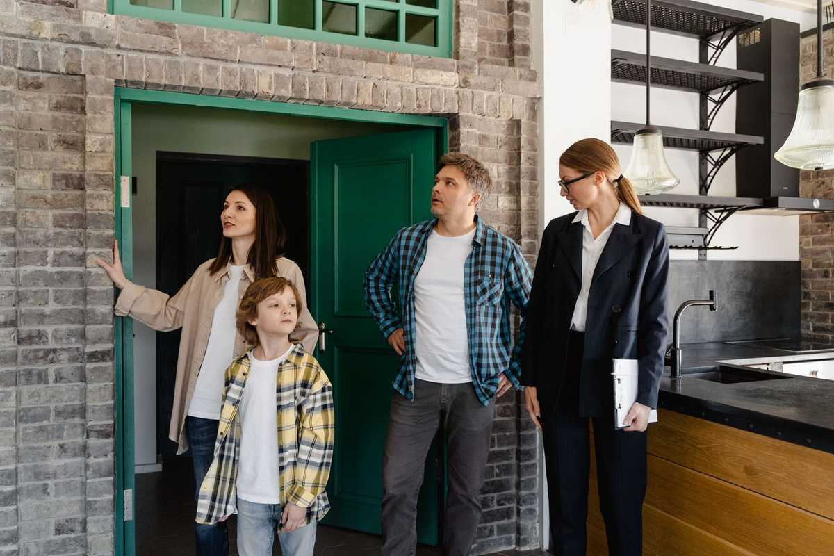 Famille et agent immobilier inspectent une maison avec cuisine moderne et portes vertes Famille et agent immobilier inspectent une maison avec cuisine moderne et portes vertes