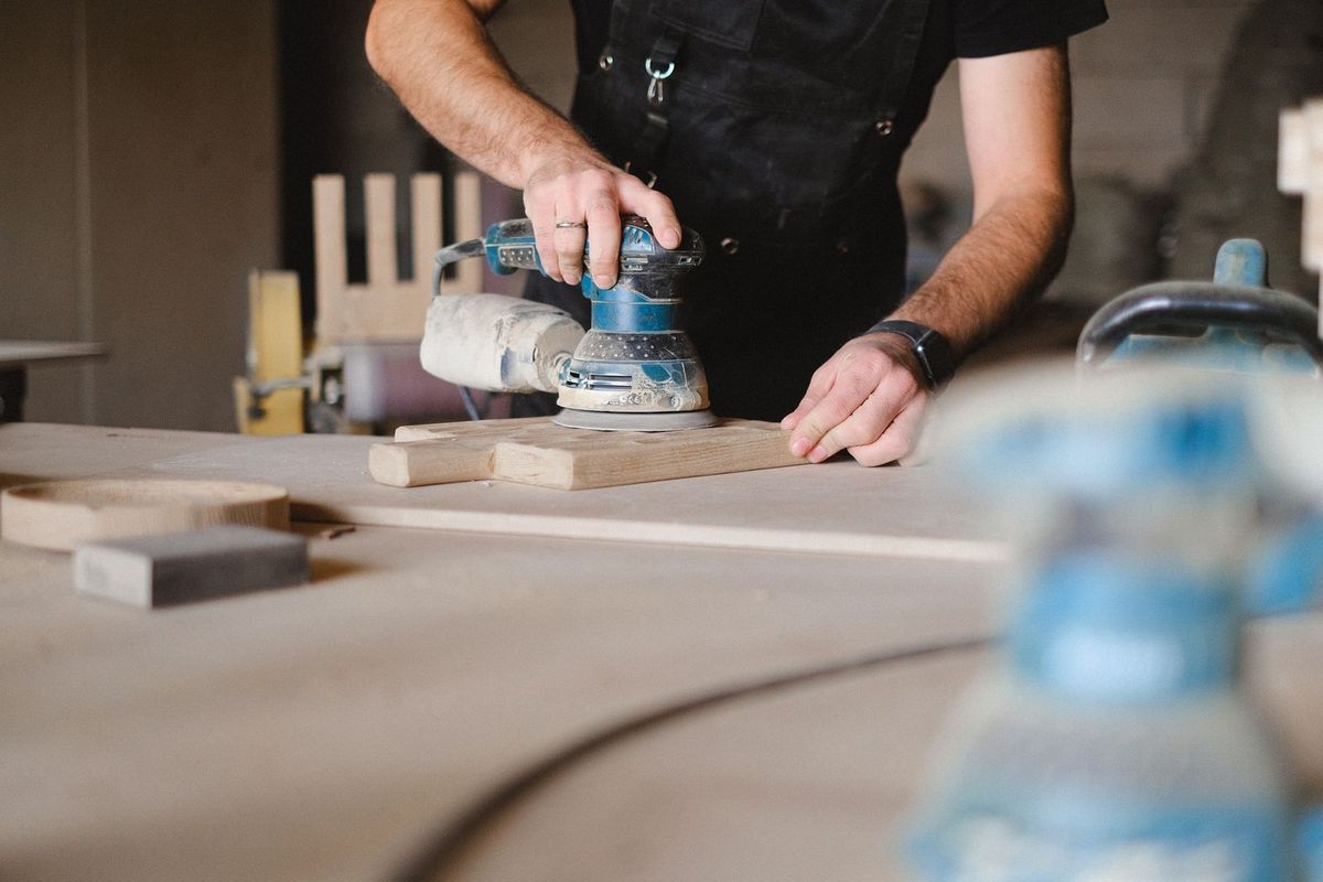 Homme utilisant une sabluse sur du bois dans un atelier Homme utilisant une sabluse sur du bois dans un atelier