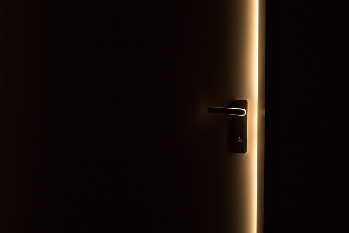 Porte métallique légèrement ouverte laissant passer un trait de lumière dans un atelier sombre Porte métallique légèrement ouverte laissant passer un trait de lumière dans un atelier sombre