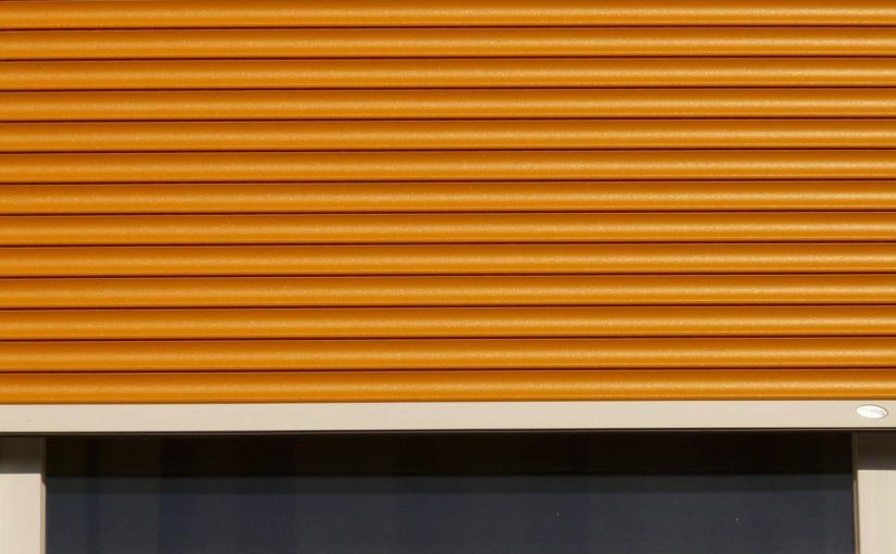 fenêtre avec volet roulant orange partiellement abaissé cadre blanc vitre sombre