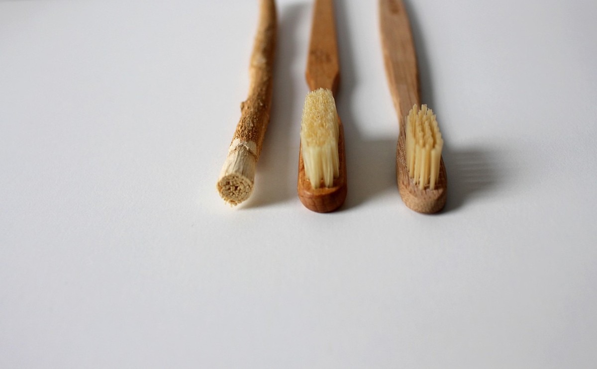 Trois brosses à dents en bois avec poils jaunes sur fond blanc Trois brosses à dents en bois avec poils jaunes sur fond blanc