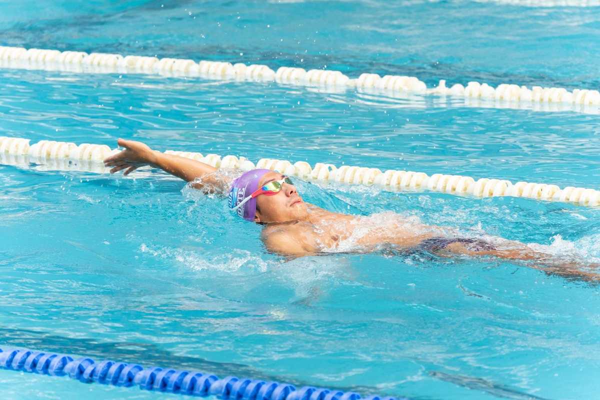 Nageur en action dans une piscine, bras étendu, lunettes et bonnet de natation, eau et cordes de division Nageur en action dans une piscine, bras étendu, lunettes et bonnet de natation, eau et cordes de division