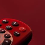 Un télécommande rouge avec plusieurs boutons noirs sur fond rouge