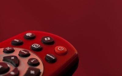 Un télécommande rouge avec plusieurs boutons noirs sur fond rouge