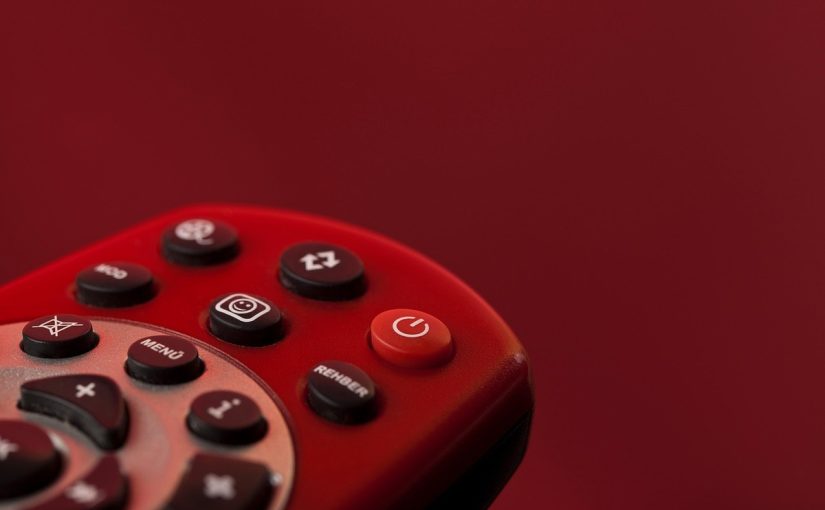 Un télécommande rouge avec plusieurs boutons noirs sur fond rouge